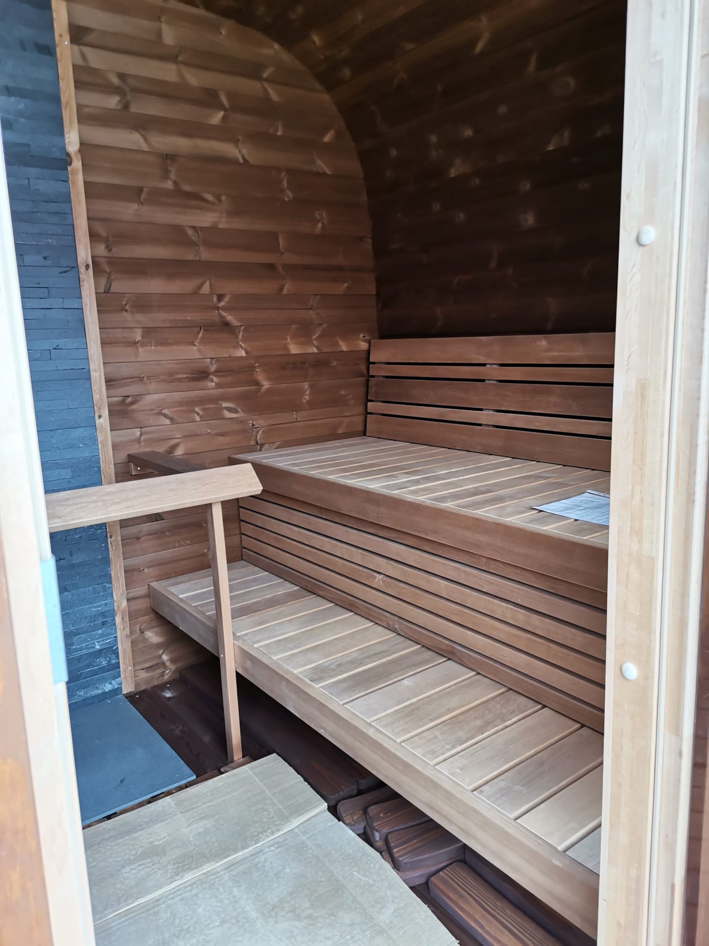 Sauna Exterior Cubus com bancos de madeira em ambiente interno.