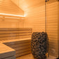 Sauna Exterior Lumi com porta de vidro e pedras visíveis.